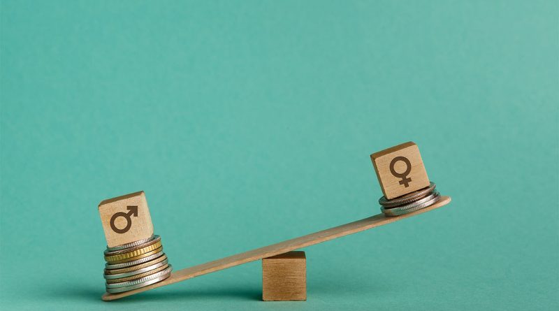 Image of a see-saw style weighing scale with the male gender symbol on one side on top of multiple coins as opposed to the female gender symbol on the other side with only 2 coins underneath to support US gender pay gap article