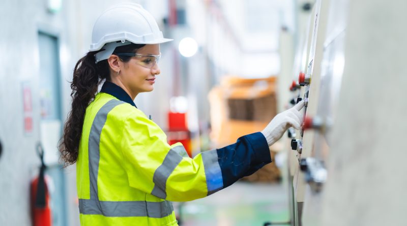 Image of a women in a high visibility vest and hard hat in a lab to support women in manufacturing article