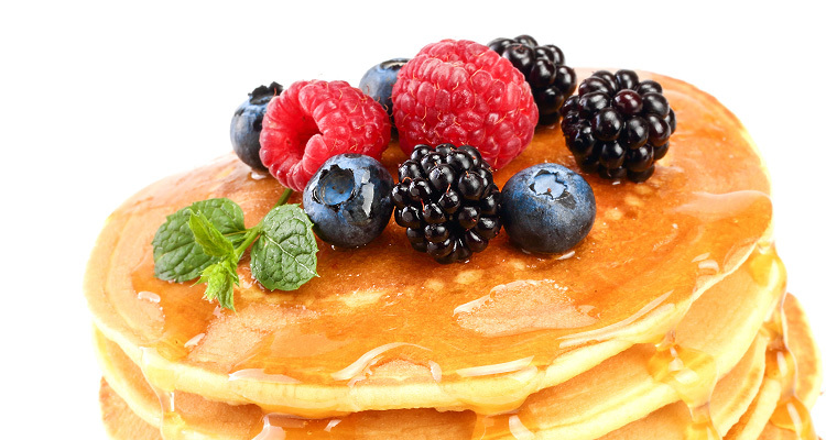 Pancakes stack with different berries and honey isolated on white background