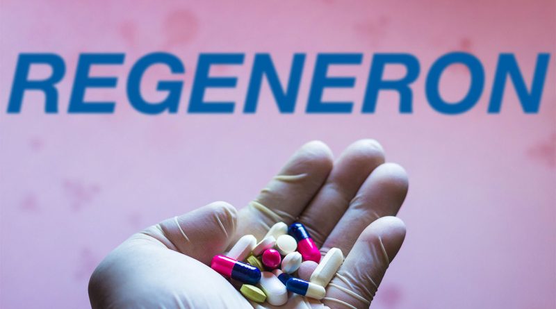 Person holding handful of different pills in front of Regeneron logo