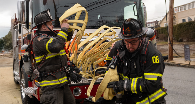 Firefighters taking hose from a fire truck