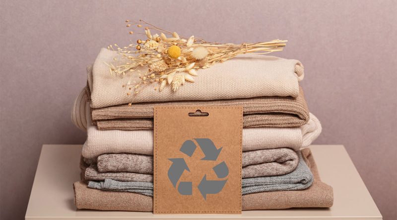 Clothes piled on table with recyclable sign on top of them to support Ethical Fashion article