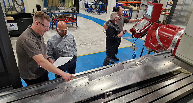 a group of people examining a large metal component