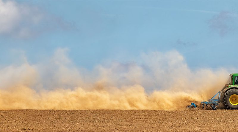 John Deere tractor driving through field to support US manufacturing article