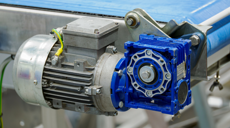 Close-up of an industrial gear motor and gearbox assembly on a conveyor system, representing modern gear manufacturing technology.