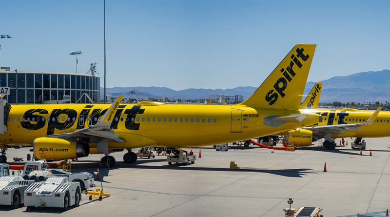 Spirit Airlines plane taxiing at a US airport during sunset with passengers boarding