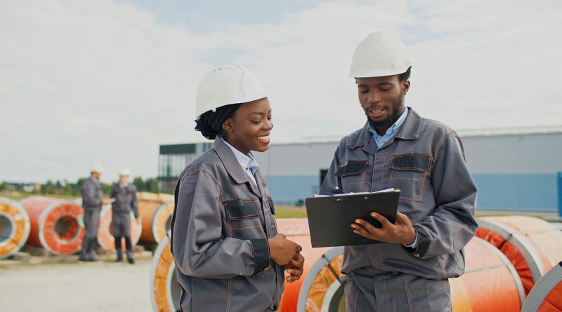 A worker in a U.S. manufacturing plant wearing safety gear beside industrial equipment