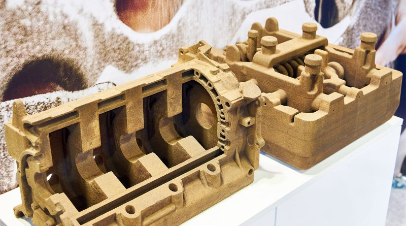 Technician operating industrial 3D printer in a U.S. manufacturing facility producing sand molds