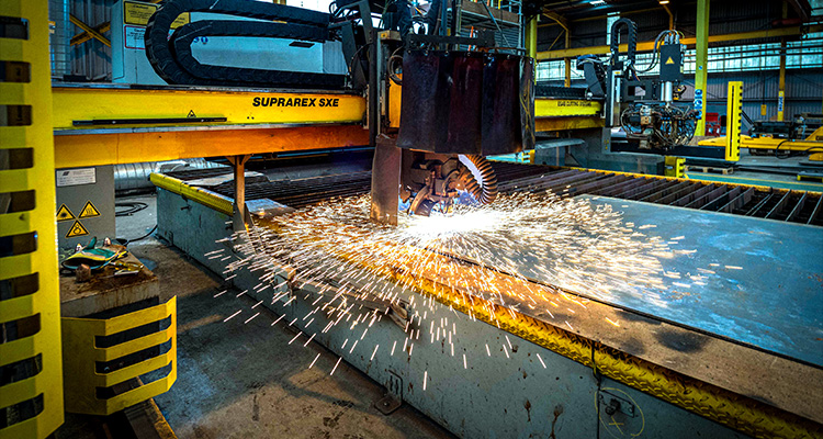 a CNC plasma cutting machine in operation, specifically a SUPRAREX SXE model, cutting a large metal sheet.