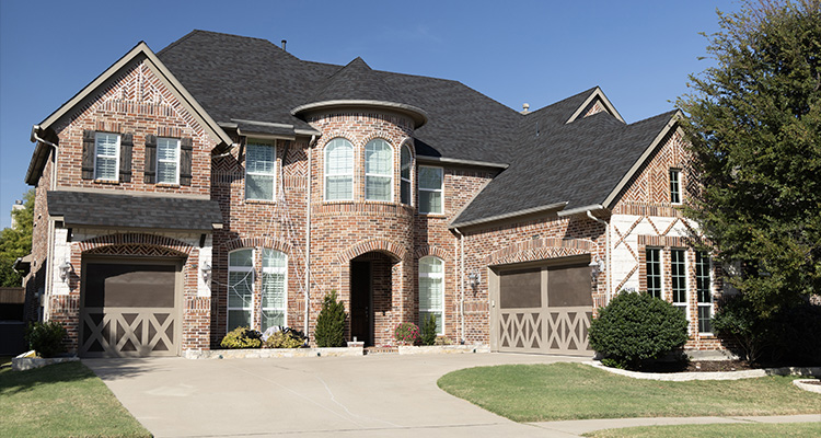 a large, two-story brick house with multiple gables and a prominent rounded turret feature at the front entrance
