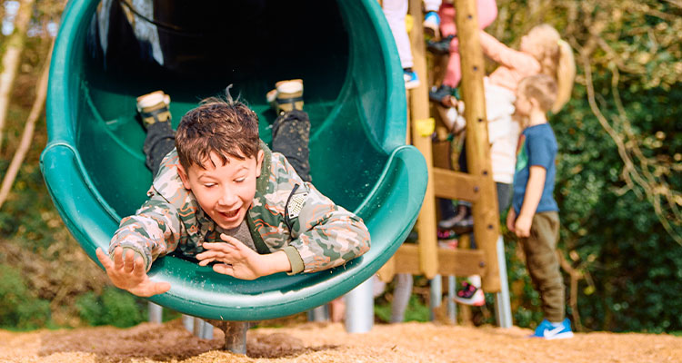 a large, enclosed, green tube slide that is part of a larger play structure