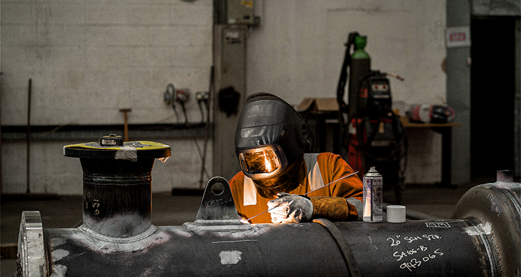 a welder working on a large pipe.