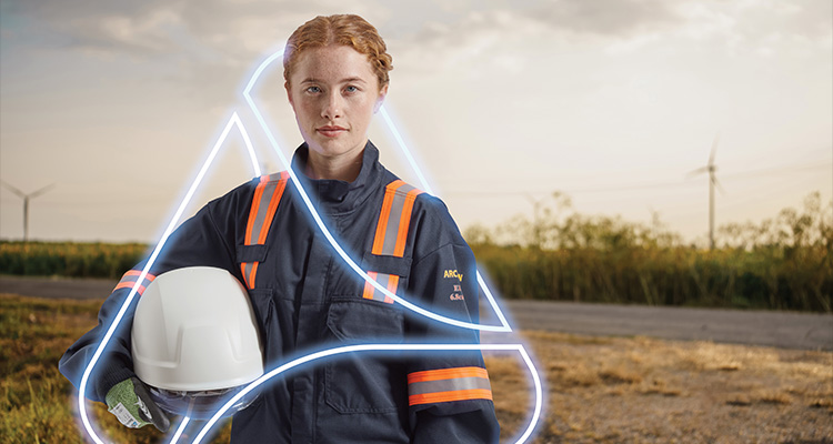 a person in a work uniform holding a hard hat in front of wind turbines, with a digital or futuristic overlay surrounding them