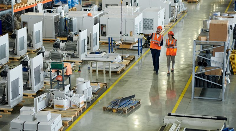 Workers on a global factory floor with slow production and halted equipment amid trade policy strain