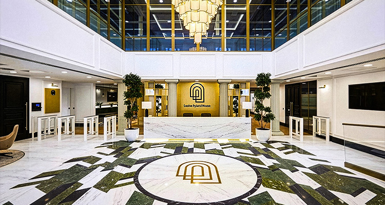 a striking contrast of white marble and dark green geometric patterns on the floor, with gold accents throughout the space, including the reception desk backdrop and central logo
