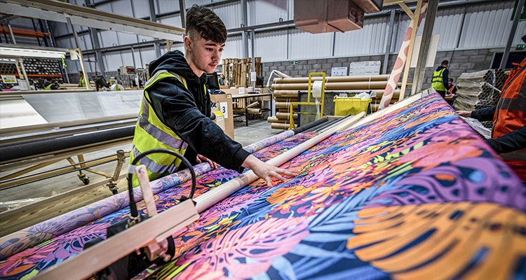 an employee at Decora Blind Systems, a manufacturer of window coverings, working with digitally printed fabric.