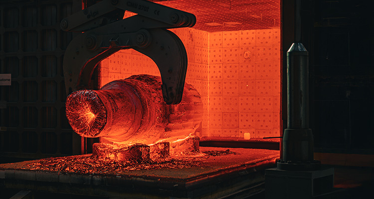 a large, glowing hot metal object being handled by a robotic arm inside an industrial furnace
