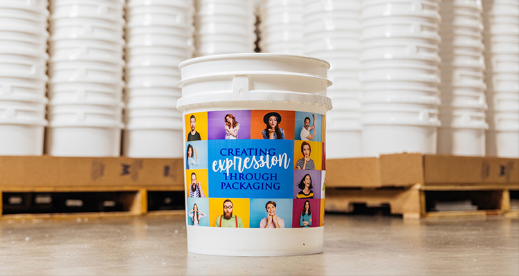 a white plastic bucket in a warehouse setting, which has been customized with a colorful label
