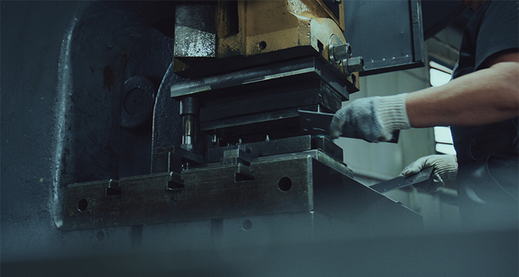 a person operating a metal stamping press machine in an industrial setting