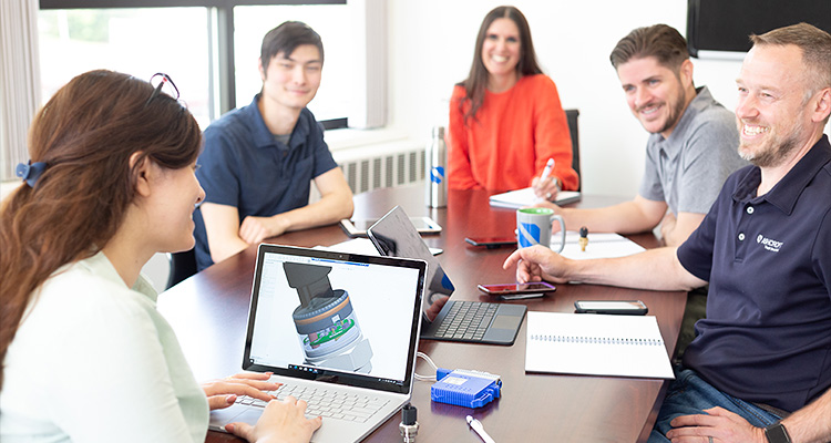 a group of five business professionals or colleagues having a meeting around a table in a modern office