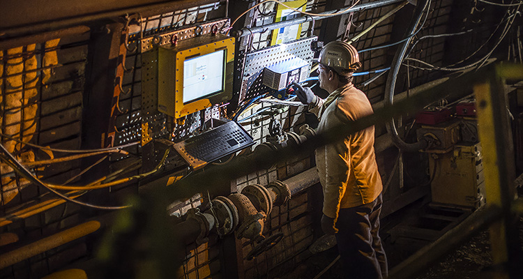 a worker in an underground mine interacting with industrial equipment