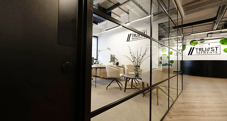 a modern office interior viewed through a dark door frame and glass partition