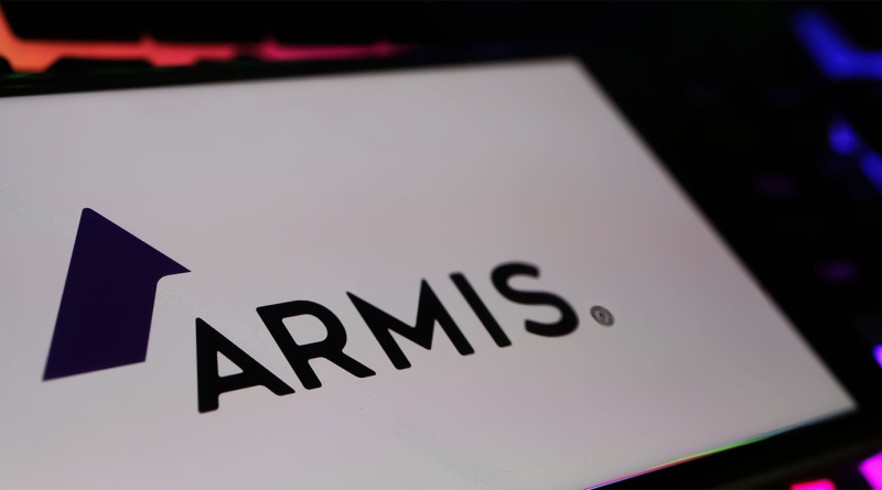 Armis logo displayed on a screen with blurred red and blue lighting in the background.